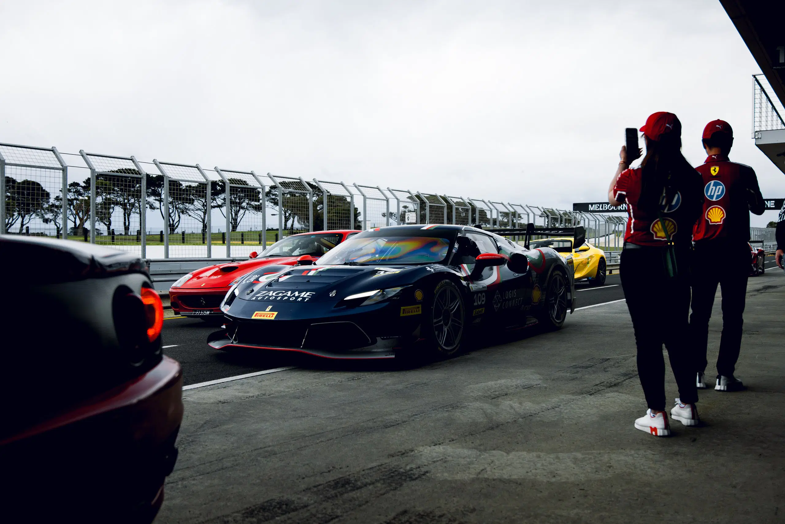 Ferraris lined up in a pit lane under an overcast sky, Ferrari Club Australia