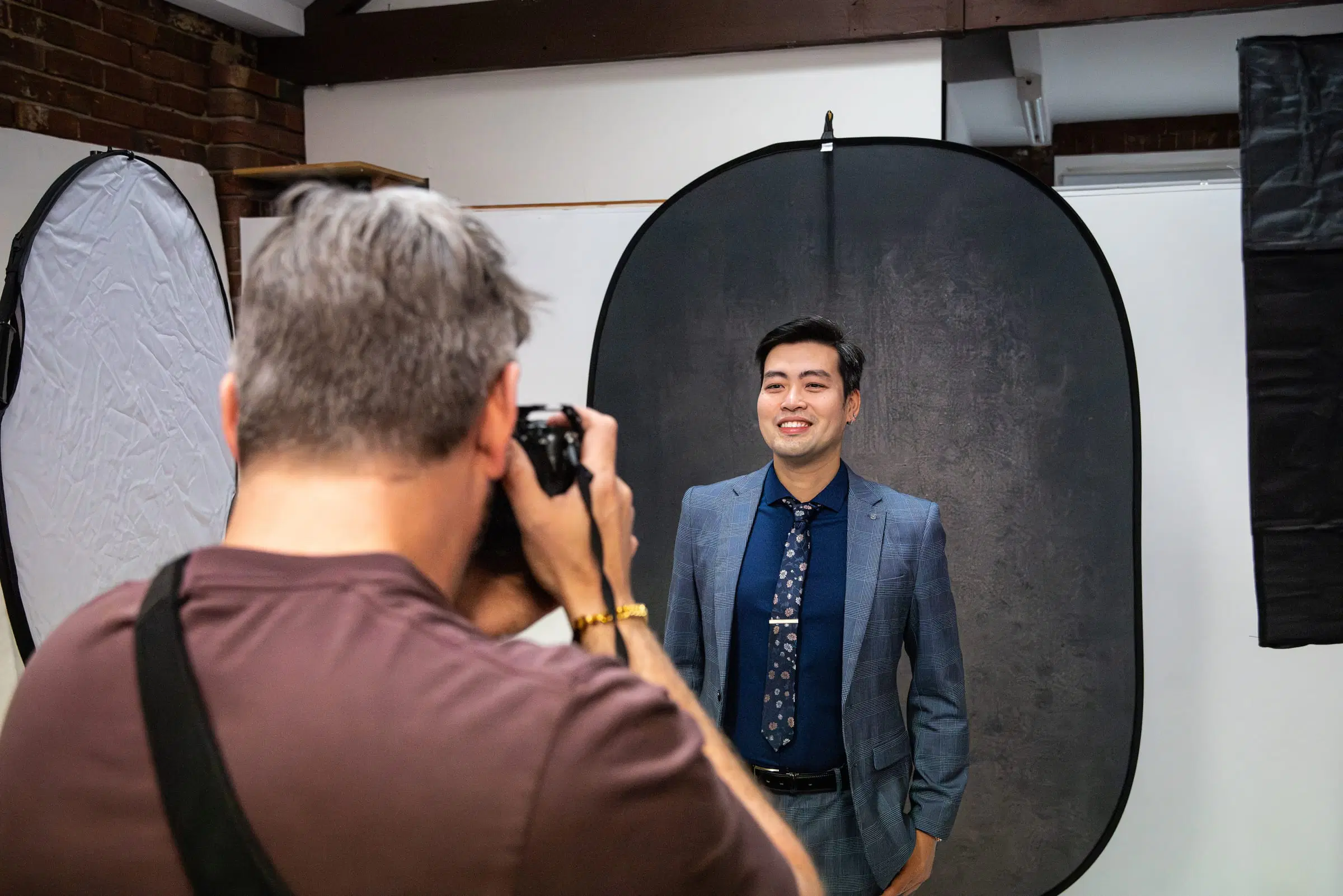 A photographer shooting a man in a blue suit against a grey backdrop